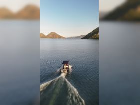 A scenic view of a boat cruising through calm waters, surrounded by picturesque hills — perfect for exploring nature and enjoying outdoor adventures.