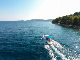 A boat navigates through crystal-clear waters along a scenic coastline, showcasing the beauty of a perfect day on the water.