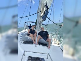 A couple relaxes on the deck of a sailboat, enjoying a sunny day on the water — perfect for a memorable sailing experience.