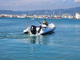 A speedboat navigates through calm waters, showcasing its sleek design and performance against a scenic harbor backdrop.