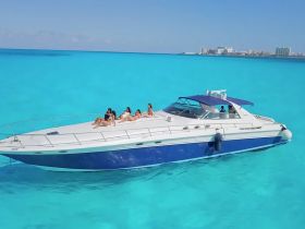 A group of friends relaxes on the deck of a luxurious boat, soaking up the sun against a stunning backdrop of turquoise waters — perfect for a day of fun on the water.