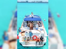 A lively group enjoys a day on the water aboard a yacht, showcasing fun and friendship against a stunning turquoise backdrop.