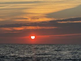 A stunning sunset over the ocean, casting vibrant colors across the sky and reflecting on the water — a perfect backdrop for evening boat cruises.
