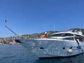 A couple enjoys sunbathing on the bow of a luxurious yacht, surrounded by stunning coastal scenery — a perfect moment for relaxation on the water.