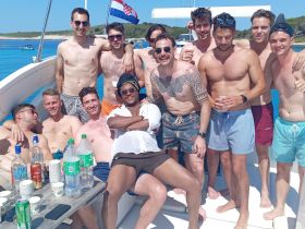 A lively group of friends enjoys a sunny day on the boat, celebrating together with drinks and laughter — perfect for summer adventures on the water.