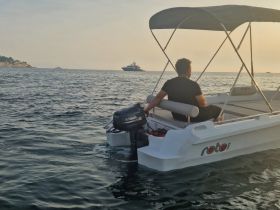 A man enjoys a serene moment on a small boat during sunset, surrounded by tranquil waters — perfect for a relaxing evening on the sea.