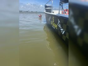 A child enjoys playing in the water near a charter boat, capturing the essence of fun water activities and family adventures on the water.