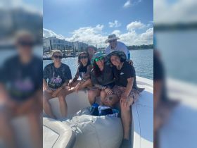 A cheerful group of friends enjoys a sunny day on a boat, capturing the essence of fun and camaraderie on the water.