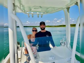 A happy couple poses on the helm of their boat, enjoying a beautiful day on the water — perfect for romantic outings or adventurous excursions.