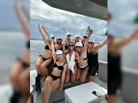 A lively group of friends celebrates together on a boat, showcasing the perfect atmosphere for a bachelorette party or summer getaway.