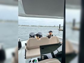 Two women relax on the deck of a boat, enjoying drinks while taking in the scenic waterfront views — a perfect moment for leisure on the water.