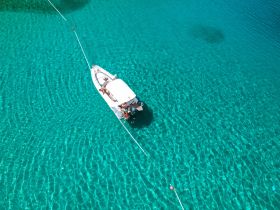 An aerial view of a boat anchored in crystal-clear turquoise waters, showcasing a perfect day for water activities and relaxation.