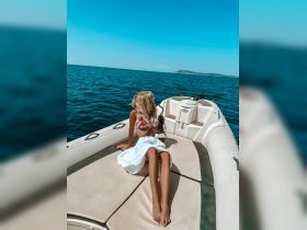 A woman relaxes on the deck of a boat, enjoying the sunny ocean view — a perfect moment for leisure and adventure on the water.