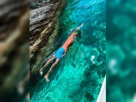 A swimmer dives into the crystal-clear waters, showcasing the vibrant underwater scenery — perfect for adventure seekers and water enthusiasts.