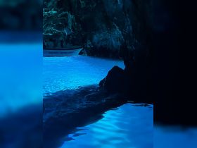 A boat navigates through a stunning blue cave, showcasing the mesmerizing underwater light reflections — a breathtaking experience for adventure seekers.