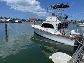 A well-maintained fishing boat docked at the marina, showcasing its sleek design against a backdrop of clear blue skies and calm waters.