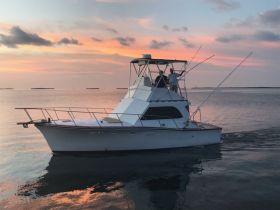 A fishing boat navigates through calm waters at sunset, creating a picturesque scene perfect for evening excursions.