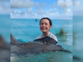 A joyful child interacts with a stingray in shallow turquoise waters, showcasing a memorable wildlife experience in the Bahamas.