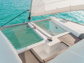 A serene view of the comfortable seating area on a catamaran, showcasing the inviting space perfect for relaxation while enjoying the turquoise waters.