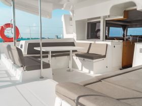 A spacious and modern interior of a boat featuring comfortable seating and a dining area, perfect for relaxing during a day on the water.