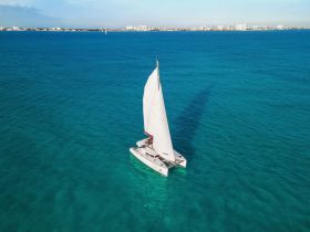 A stunning aerial view of a catamaran sailing through crystal-clear turquoise waters, showcasing the beauty of maritime adventures.