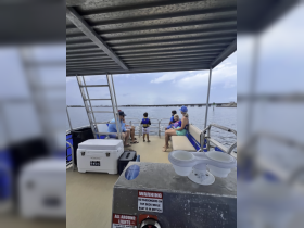 A family enjoys a day on the water aboard a pontoon boat, with children in life jackets exploring the deck — perfect for family outings and water adventures.