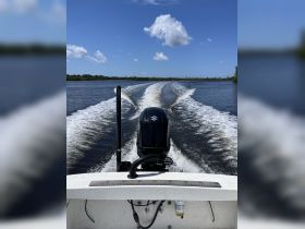 A dynamic view from the back of a speedboat cruising through calm waters, showcasing the powerful engine and wake created behind.