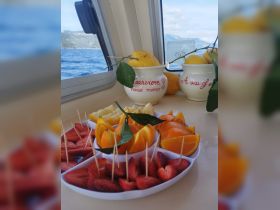 A vibrant display of fresh fruit on a boat, featuring strawberries, oranges, and lemons — perfect for a refreshing snack while enjoying the sea breeze.