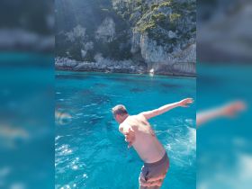A man prepares to jump into the crystal-clear waters, showcasing the thrill of swimming and adventure in a stunning coastal setting.