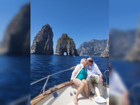 A couple shares a romantic kiss aboard a boat with stunning rock formations in the background, perfect for memorable moments on the water.