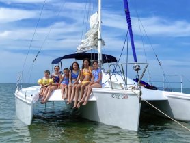 A joyful group of children enjoys a day on a catamaran, showcasing fun and adventure on the water — perfect for family outings and summer memories.