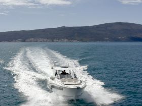 A sleek speedboat glides through the water, leaving a trail of white foam behind, showcasing the beauty of a day on the open sea.