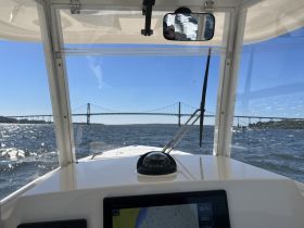 View from the helm of a boat, showcasing the console and a bridge in the distance — perfect for navigation enthusiasts and boating adventures.