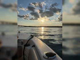 A serene sunset view from the bow of a boat, showcasing the tranquil waters and dramatic cloud formations — perfect for evening cruises.