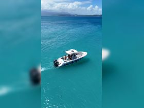 A sleek boat navigates through crystal-clear turquoise waters, showcasing a perfect day on the water with friends.