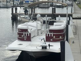 A pontoon boat docked at the marina, showcasing its spacious seating and amenities, perfect for leisurely outings on the water.