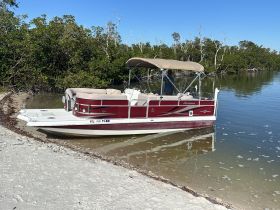 A pontoon boat named 'Hurricane' is docked in a serene mangrove setting, showcasing its spacious design perfect for leisurely outings.