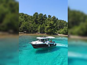 A sleek speedboat navigates through crystal-clear turquoise waters, surrounded by lush greenery — perfect for exploring hidden coves and enjoying sunny days on the water.