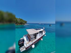 A scenic view of a boat anchored in crystal-clear turquoise waters, with guests enjoying the sun and the beautiful surroundings — perfect for a relaxing day on the water.