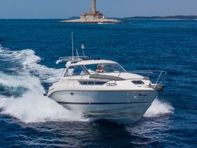 A sleek boat speeds through vibrant blue waters, showcasing a picturesque lighthouse in the background — perfect for adventure seekers and scenic tours.