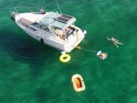 A lively scene featuring guests enjoying a sunny day on the water, with one person floating and others relaxing on a boat — perfect for summer adventures and water fun.