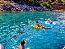 Two friends enjoy a sunny day floating in crystal-clear waters, showcasing the perfect summer getaway experience.