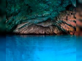 A stunning view of a cave with vibrant blue water reflecting the colorful rock formations — a perfect spot for exploration and adventure.