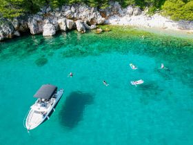 A vibrant scene of people enjoying the crystal-clear waters, with a boat anchored nearby — perfect for a fun day of swimming and relaxation.