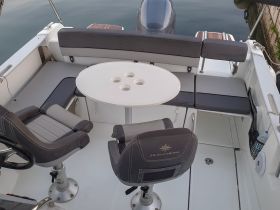 Interior view of a well-appointed boat helm and seating area, showcasing comfortable seating and a central table — perfect for relaxing while on the water.