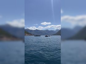 A picturesque view of boats on calm waters surrounded by stunning mountain scenery, perfect for showcasing the beauty of coastal adventures.