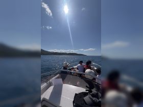 A group enjoys a sunny day on a boat, taking in the beautiful ocean views and the surrounding landscape — perfect for family outings or group adventures.