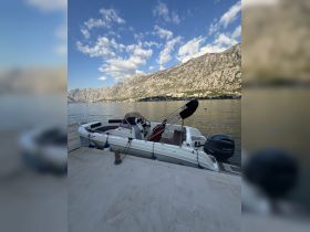 A sleek speedboat docked at a picturesque waterfront, surrounded by stunning mountain scenery — perfect for exploring the serene waters.