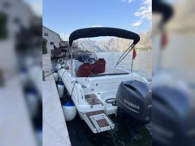 A sleek speedboat docked along the picturesque waterfront, showcasing its modern design and stunning mountain backdrop — perfect for exploring scenic coastlines.