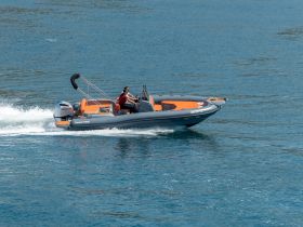 A speedboat glides through the clear waters with two passengers onboard, showcasing the thrill of a day on the water.